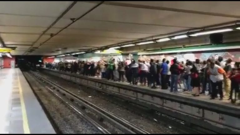 Usuarios del metro hacen una ola mientras esperan el último tren