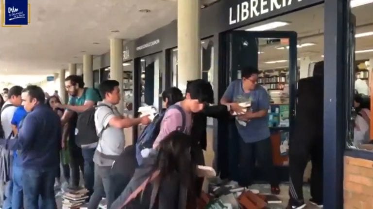 Estudiantes de la UNAM recogen los libros que habían sido saqueados durante una protesta