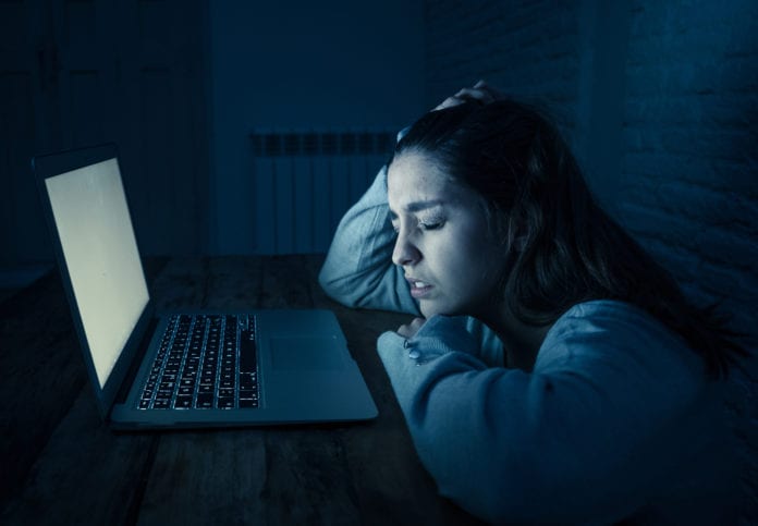 Mujer joven frente a una laptop sintiendo angustia
