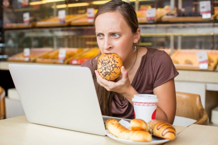 Mujer con estrés come mientras trabaja