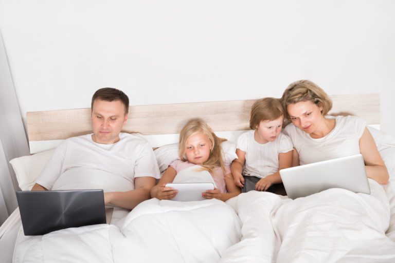 Familia joven con computadora en la cama