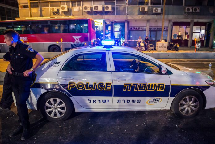 Tel Aviv, Israel - October 18, 2015. Police officer stands next to police car on the street in Tel Aviv